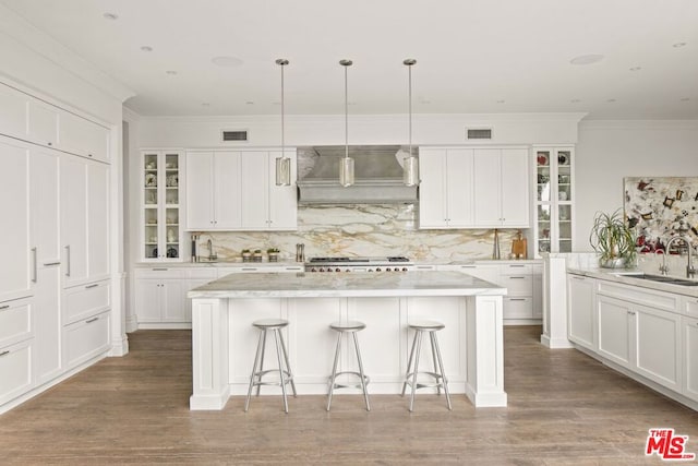 kitchen with sink, a center island, custom range hood, pendant lighting, and stove