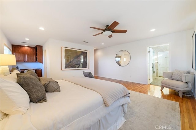 bedroom with ceiling fan, ensuite bath, and light wood-type flooring