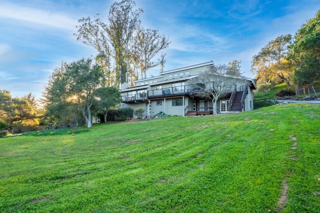 back of property featuring a wooden deck and a lawn