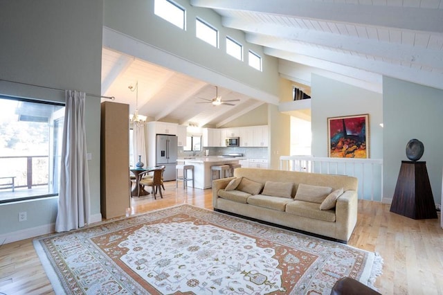 living room with beam ceiling, high vaulted ceiling, an inviting chandelier, and light hardwood / wood-style floors