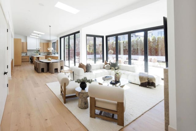 bedroom with multiple windows, a skylight, and light hardwood / wood-style flooring