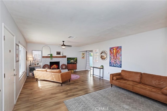 living room with a fireplace, wood-type flooring, and ceiling fan