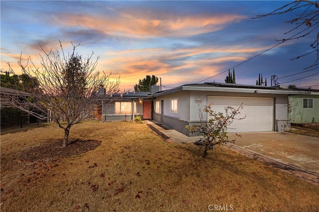 ranch-style house featuring a garage and a yard