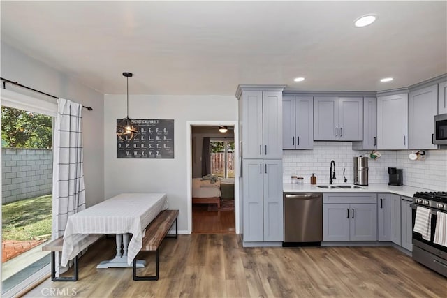 kitchen with sink, gray cabinetry, dark hardwood / wood-style flooring, decorative backsplash, and stainless steel appliances