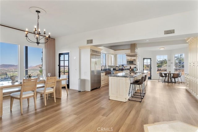 kitchen featuring a chandelier, dark stone counters, pendant lighting, island exhaust hood, and stainless steel appliances