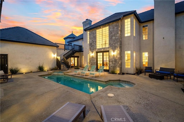 pool at dusk with an in ground hot tub and a patio area