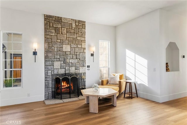 living area featuring plenty of natural light, a stone fireplace, and hardwood / wood-style floors