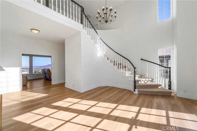 entrance foyer with hardwood / wood-style flooring, a high ceiling, and an inviting chandelier