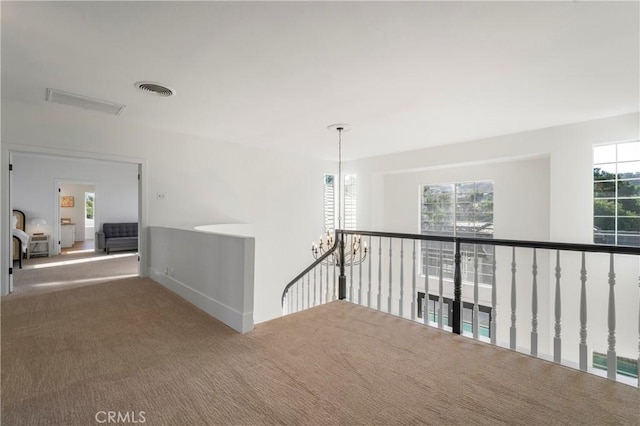 hallway featuring carpet flooring, a wealth of natural light, and a chandelier