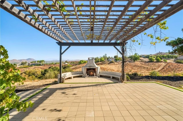 view of patio / terrace with a mountain view, a pergola, and an outdoor fireplace