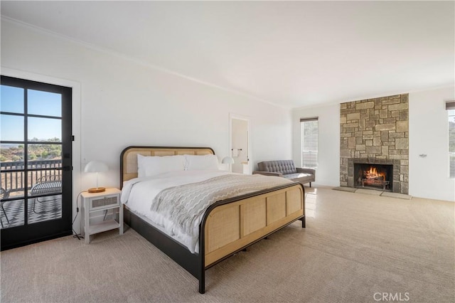 carpeted bedroom with a stone fireplace and access to outside