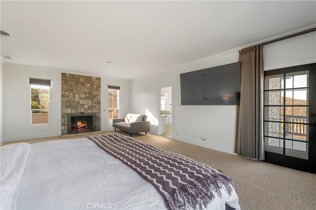 bedroom with multiple windows, ornamental molding, a stone fireplace, and light carpet