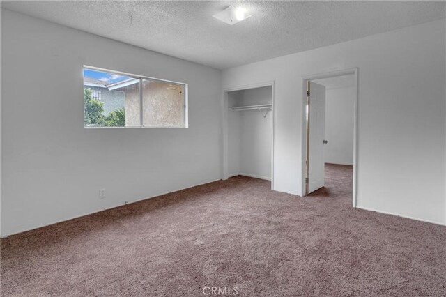 unfurnished bedroom with carpet flooring, a textured ceiling, and a closet