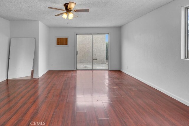 spare room featuring wood finished floors, a textured ceiling, a ceiling fan, and baseboards