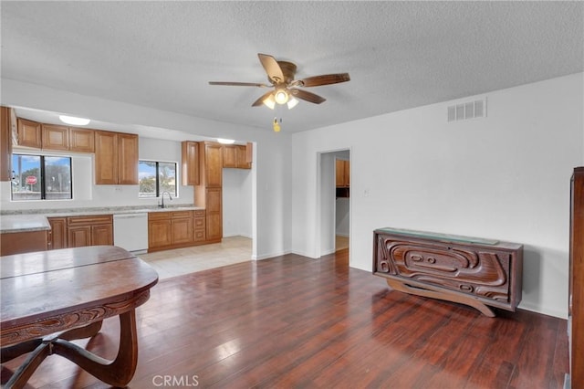 kitchen featuring a ceiling fan, white dishwasher, light wood finished floors, light countertops, and visible vents