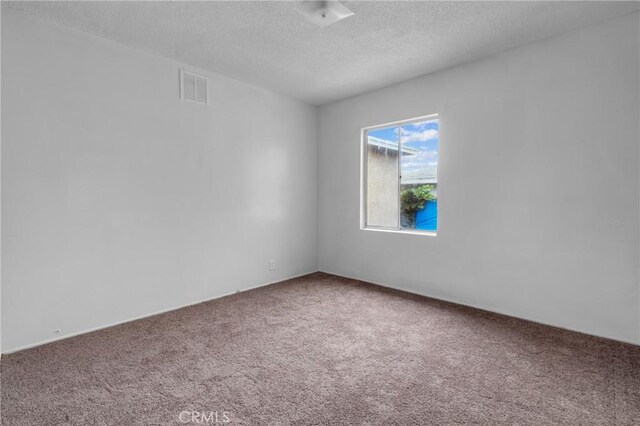 carpeted empty room with visible vents and a textured ceiling