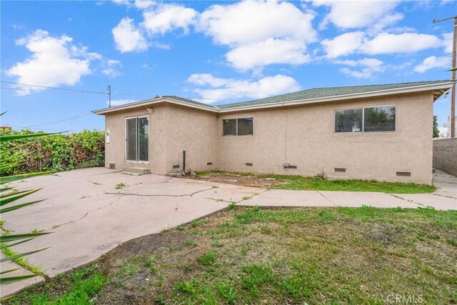 rear view of property featuring stucco siding, crawl space, fence, and a patio