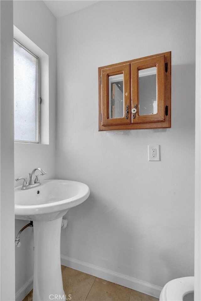 bathroom featuring tile patterned floors, baseboards, and toilet