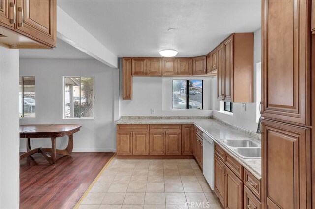 kitchen featuring dishwasher, brown cabinetry, a sink, and light wood finished floors