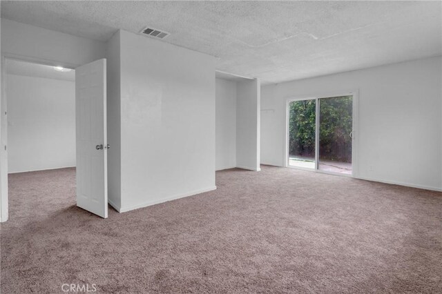 spare room featuring a textured ceiling, carpet, and visible vents