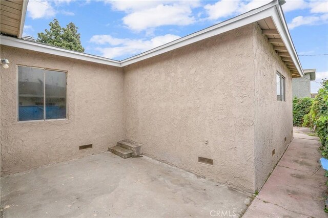 view of property exterior featuring stucco siding, crawl space, and a patio