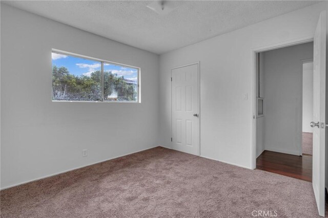 unfurnished bedroom featuring a textured ceiling and carpet