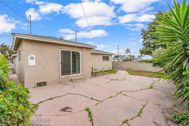 rear view of house featuring fence private yard, a patio area, and stucco siding