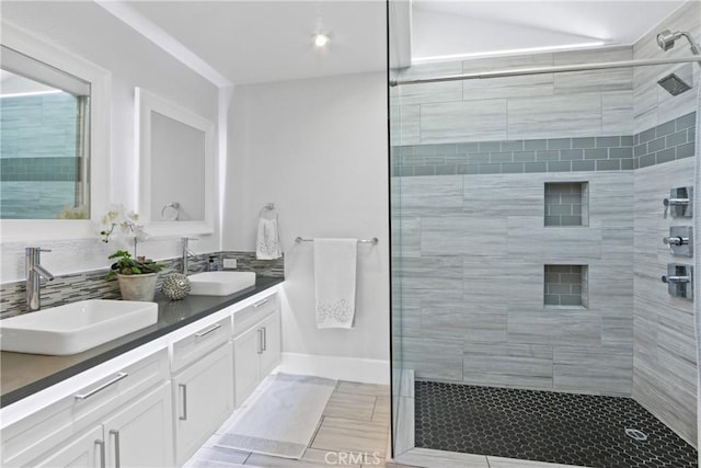 bathroom with tasteful backsplash, vanity, tile patterned flooring, and a tile shower