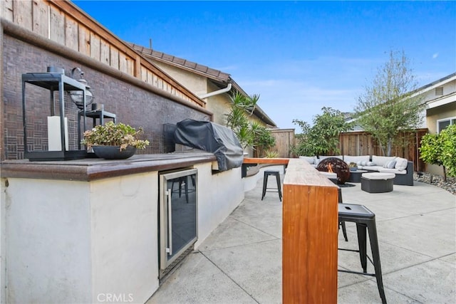 view of patio / terrace featuring an outdoor kitchen, grilling area, exterior bar, beverage cooler, and an outdoor living space with a fire pit