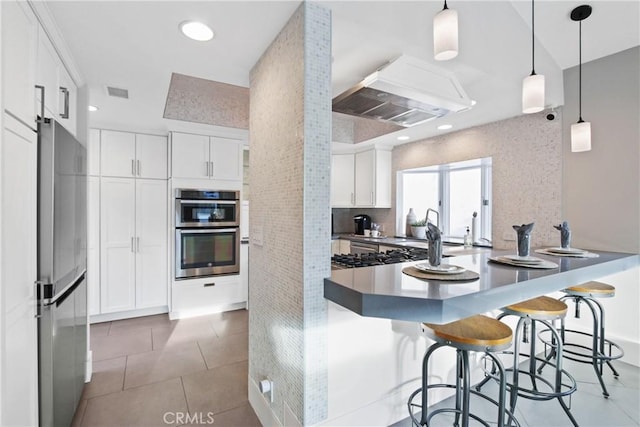 kitchen featuring stainless steel appliances, white cabinetry, hanging light fixtures, and a kitchen breakfast bar