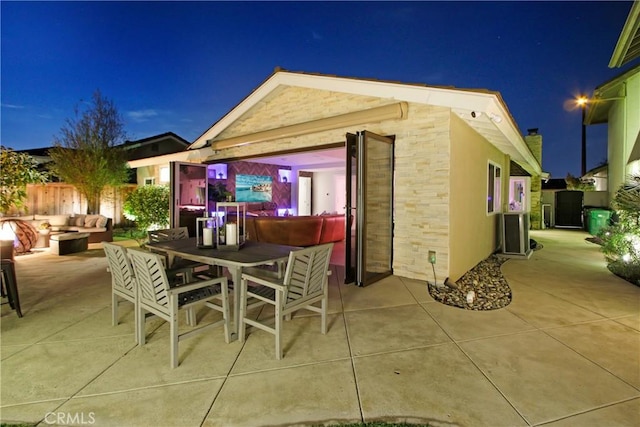 patio at night featuring an outdoor structure and an outdoor living space with a fire pit