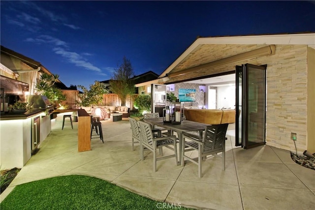 patio at twilight featuring an outdoor kitchen and grilling area