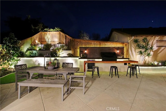 patio at twilight featuring a grill and an outdoor bar