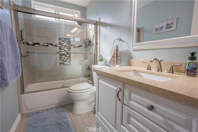 full bathroom featuring vanity, shower / bath combination with glass door, and toilet