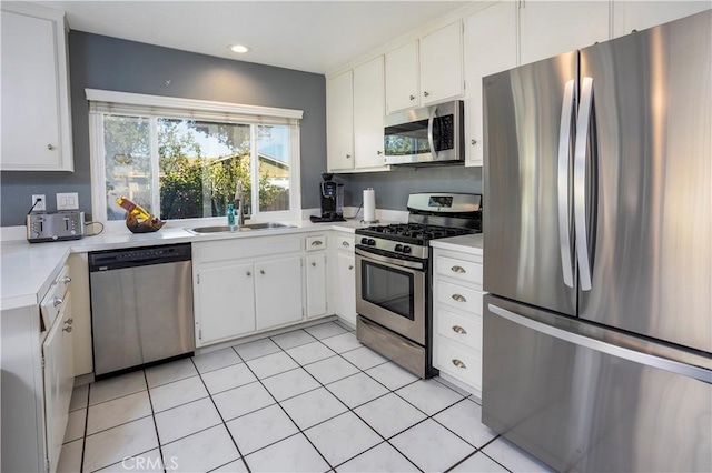 kitchen with stainless steel appliances, sink, light tile patterned floors, and white cabinets