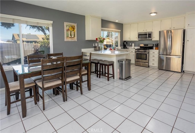 kitchen with plenty of natural light, stainless steel appliances, kitchen peninsula, and light tile patterned flooring