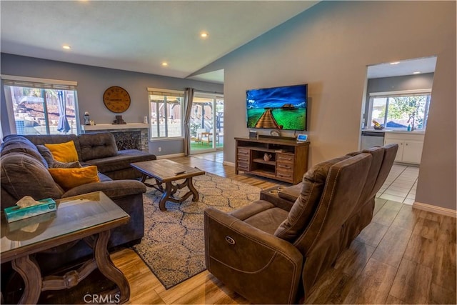 living room featuring lofted ceiling, a wealth of natural light, and light hardwood / wood-style floors