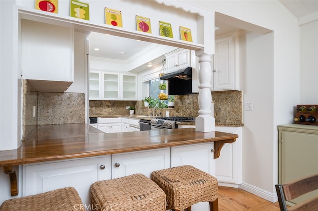 kitchen featuring range, kitchen peninsula, and white cabinets