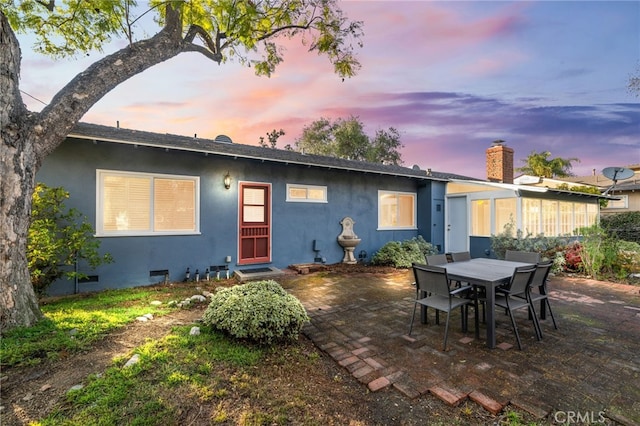 back house at dusk featuring a patio