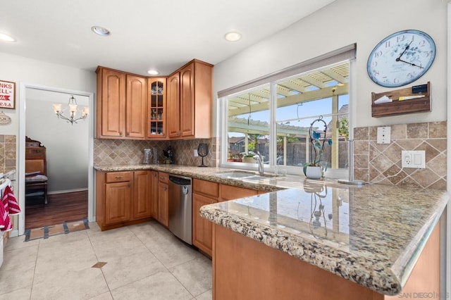 kitchen with sink, tasteful backsplash, light tile patterned floors, stainless steel dishwasher, and light stone countertops