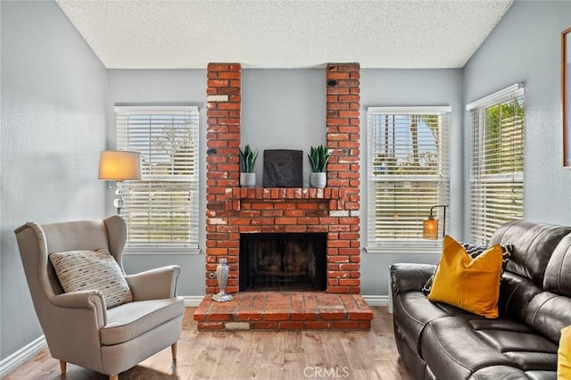 living room with a fireplace, light hardwood / wood-style floors, and a textured ceiling