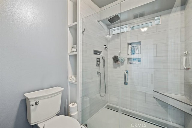 bathroom featuring toilet and a shower with door