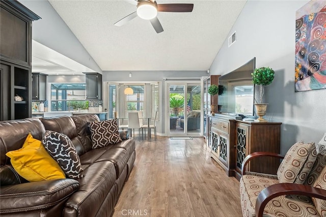 living room featuring ceiling fan, lofted ceiling, light hardwood / wood-style floors, and plenty of natural light