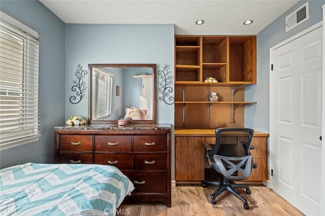 bedroom with light hardwood / wood-style floors and a textured ceiling