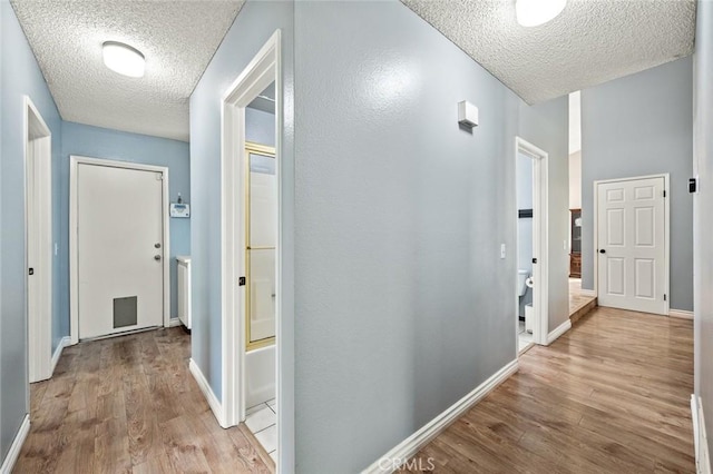 hallway featuring light hardwood / wood-style floors and a textured ceiling