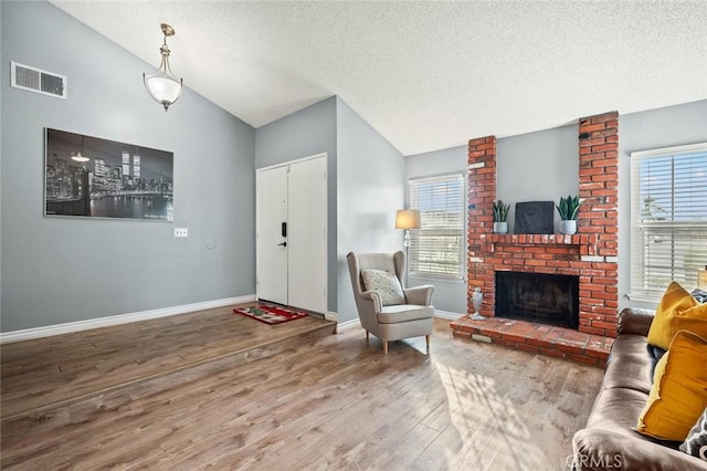 living room with a fireplace, vaulted ceiling, hardwood / wood-style floors, and a textured ceiling