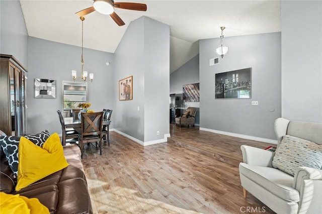 living room with wood-type flooring, lofted ceiling, and ceiling fan with notable chandelier