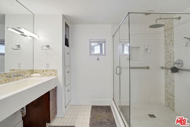 bathroom with tile patterned flooring, vanity, walk in shower, and decorative backsplash