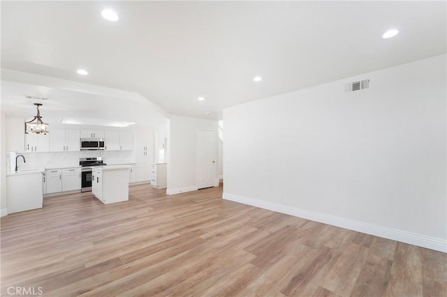 unfurnished living room with sink, an inviting chandelier, and light hardwood / wood-style floors