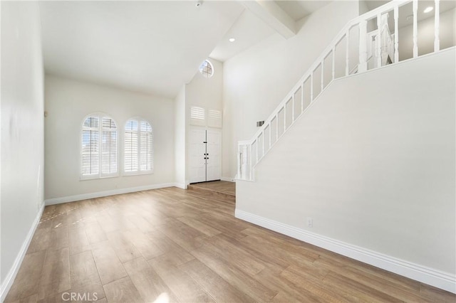 foyer entrance with beamed ceiling and light wood-type flooring